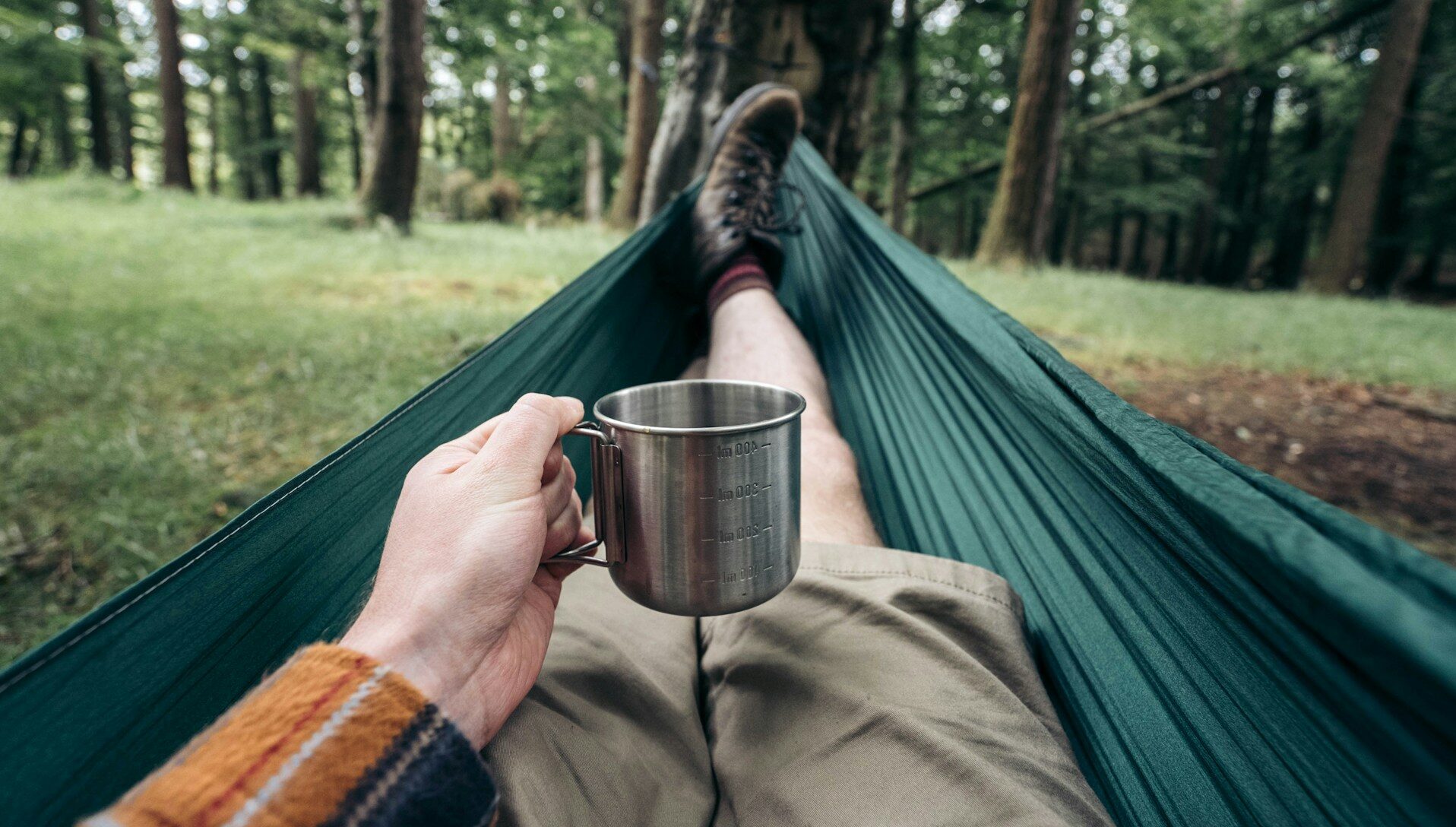 一杯のコーヒーを飲みながらハンモックに横たわる人
